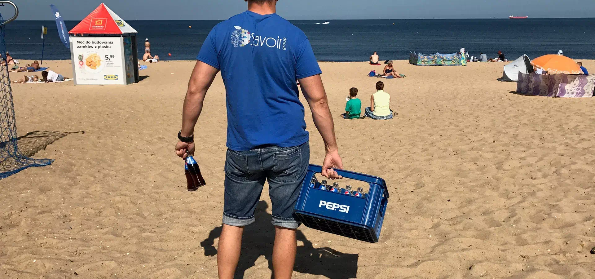 Mężczyzna z skrzynką Pepsi na plaży